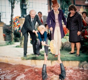 Augustus gets sucked way in the chocolate river as Charlie and Grandpa try to help him.